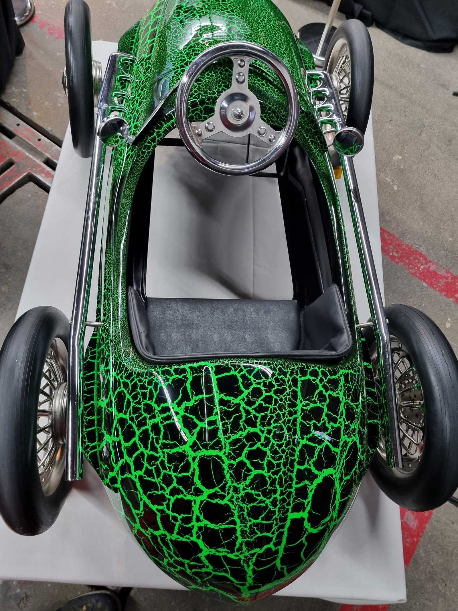 Auf einem Tisch steht ein grünes Spielzeugauto mit Lenkrad.